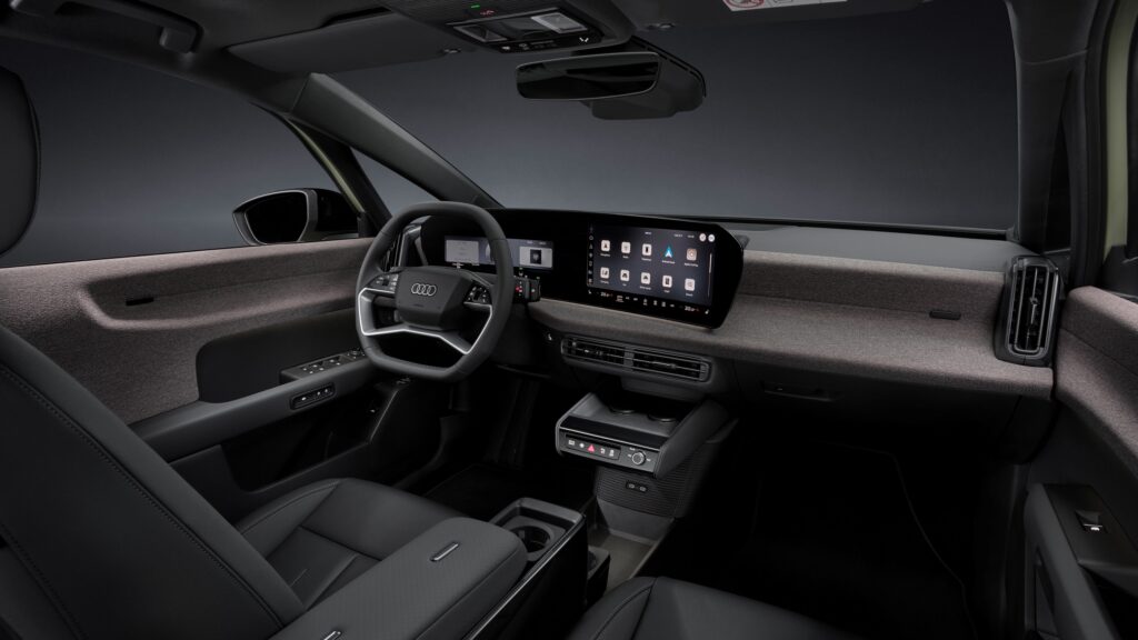 Audi A2 e-tron Studio static photo, interior, cockpit from the passenger side, multifunction steering wheel, MMI panoramic display, MMI touch display, fabric-covered surface softwrap, centre armrest with modular Fidlock fastening system and phone tray with inductive charging capability