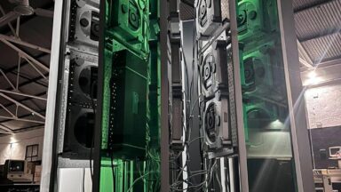 A vertical photo showing the size of the Cray-1 replica project. A large C-shaped tower stands lit up with green accent lighting.