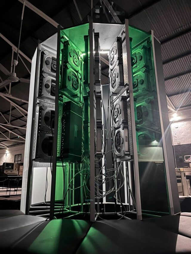 A vertical photo showing the size of the Cray-1 replica project. A large C-shaped tower stands lit up with green accent lighting.
