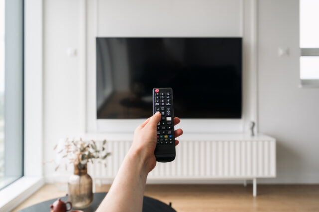 Smart TV is mounted on the wall in a contemporary living room while a person holds a remote control .
