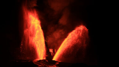 Two lava fountains erupt near to each other, with each tilting off in opposite directions.