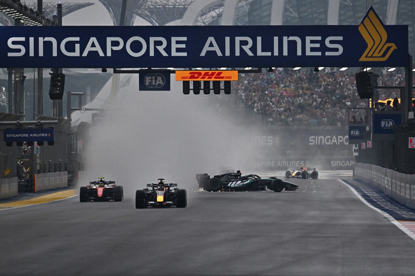 Mercedes' British driver George Russell (centre R) crashes as Ferrari's British driver Lewis Hamilton (L) and Red Bull Racing's Dutch driver Max Verstappen (2L) steer their car during the sprint race ahead of the Formula One Singapore Grand Prix at the Marina Bay Street Circuit in Singapore on October 10, 2026. (Photo by Lillian SUWANRUMPHA / AFP)