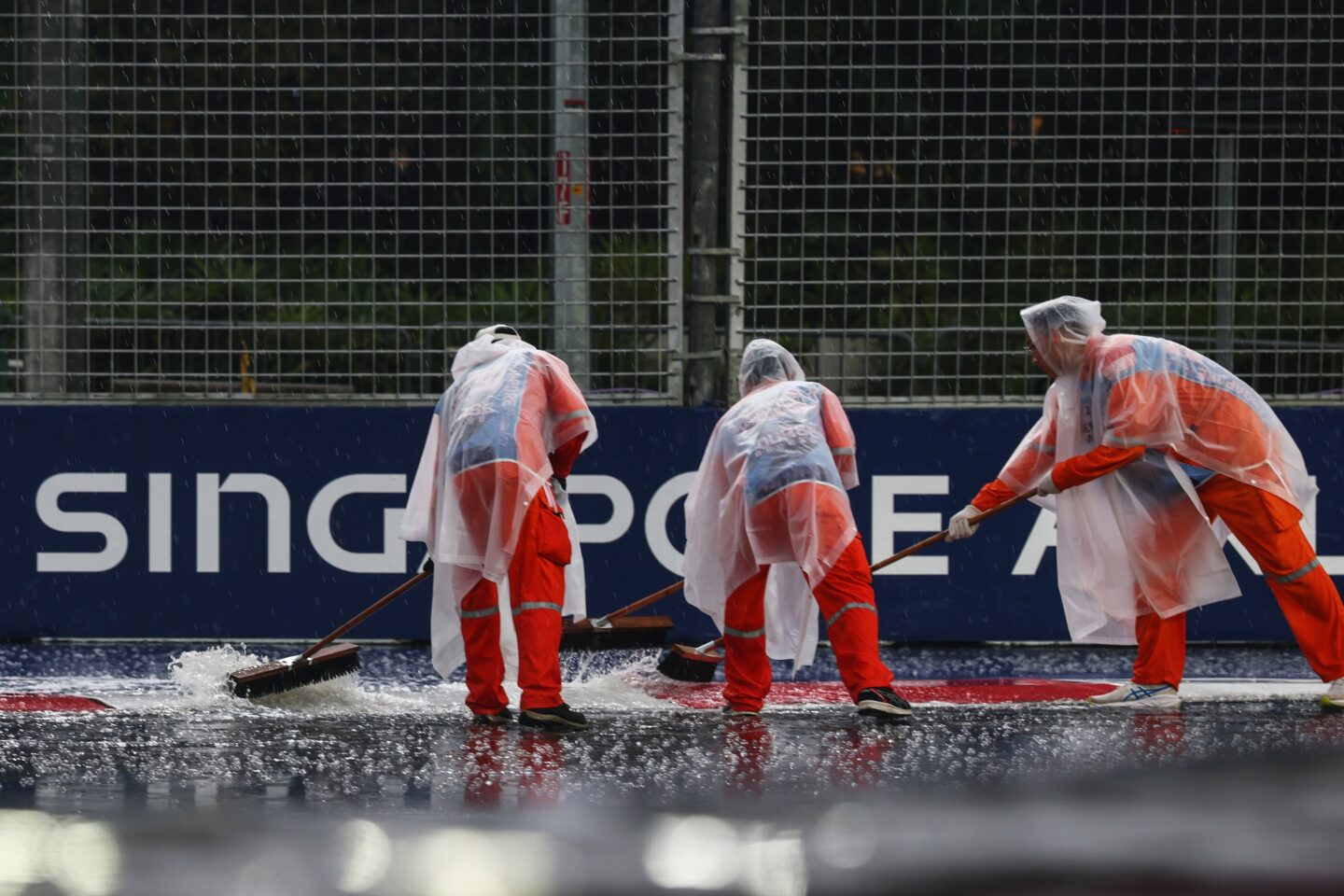 SINGAPORE, SINGAPORE - OCTOBER 10: Marshals sweep away the standing water on track as the rain falls prior to the Sprint ahead of the F1 Grand Prix of Singapore at Marina Bay Street Circuit on October 10, 2026 in Singapore, Singapore. (Photo by Mark Thompson/Getty Images)