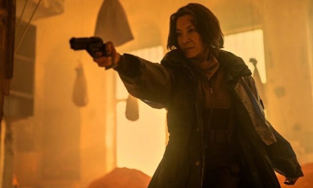 Asian woman in trench coat pointing a gun