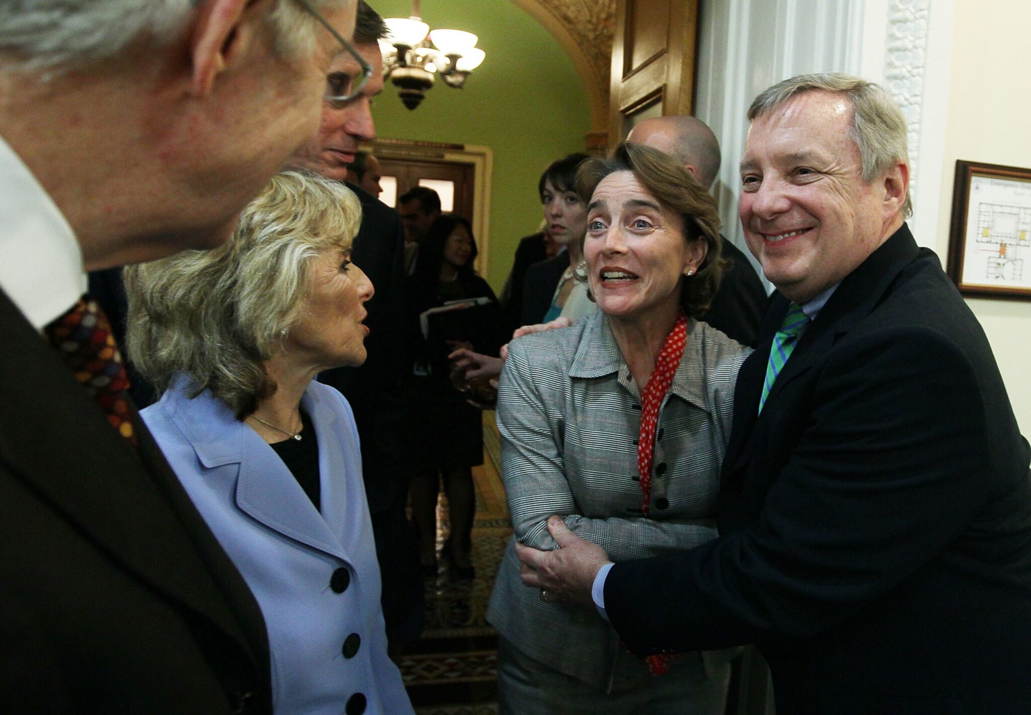 A group of US senators smiling and celebrating with each other after passage of a bill.