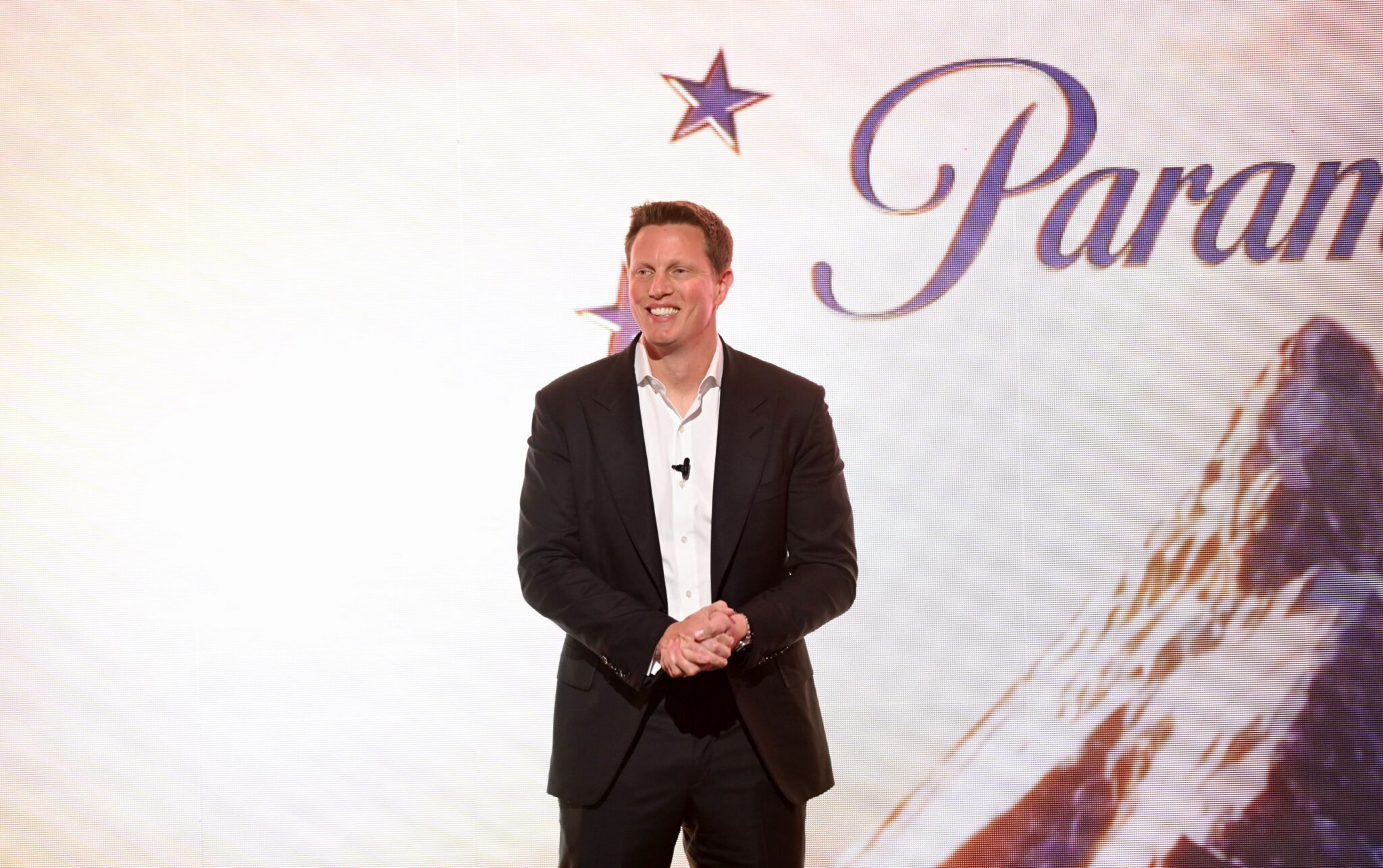 David Ellison stands and smiles in front of a backdrop with a Paramount logo.