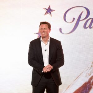 David Ellison stands and smiles in front of a backdrop with a Paramount logo.