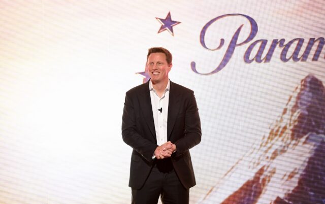 David Ellison stands and smiles in front of a backdrop with a Paramount logo.