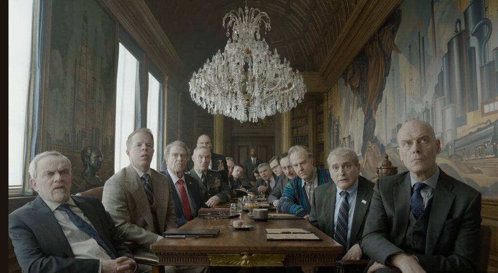 crowd of men in suits seated at a table and peering toward the camera