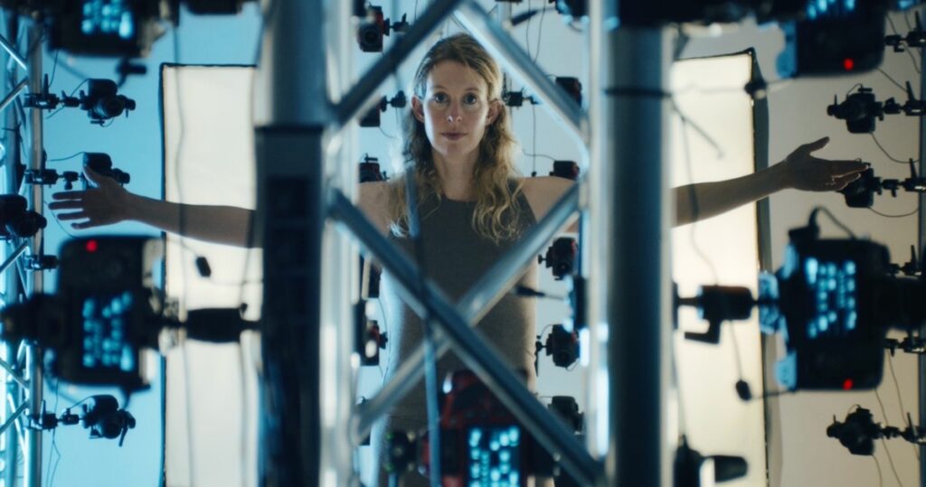 blonde woman standing, arms outstretched, in a lattice of technology.