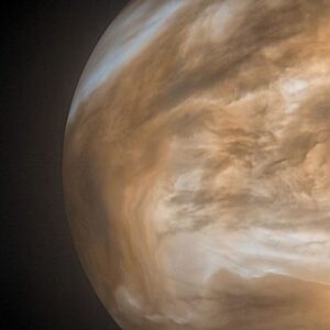 Image of a yellow brown planet on the right of a wide field view.