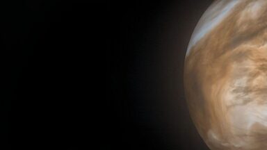 Image of a yellow brown planet on the right of a wide field view.