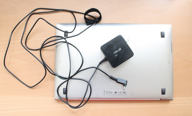 The underside of the Zenbook and its mercifully small power brick with long, unruly cord.