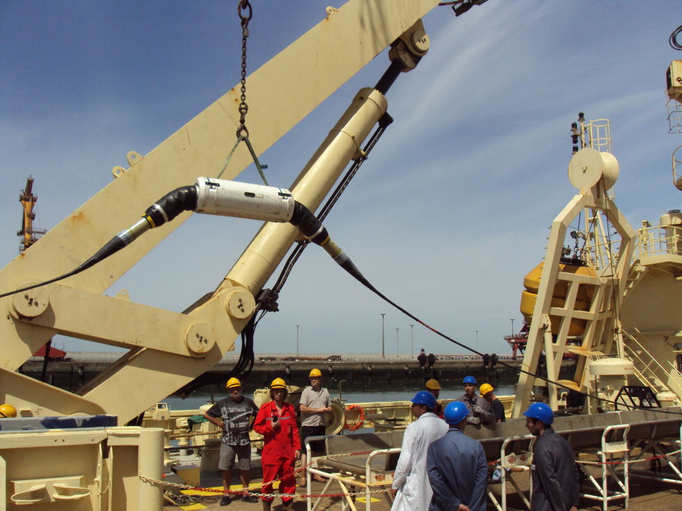 A submarine cable laying ship in action. Here the submarine cable, with an amplifier in the middle, is being hoisted onto the ship.